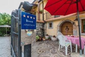 a patio with a table and a red umbrella at Apartments Sušanj in Matulji