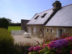 a stone house with white chairs and flowers in front of it at P'ty gîte de Bréharadec in Goulien