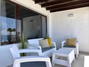un patio con sillas blancas, un sofá y una mesa en Apartamento Seaview, en Puerto del Carmen