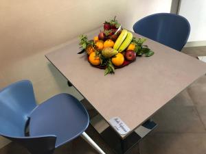 ナポリにあるNapoli Com'eraの青い椅子2脚付きのテーブルに果物を盛り付けた鉢