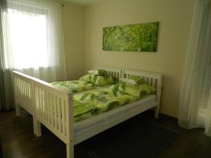 バラトンフゥルドヴァールにあるGreentó Apartmanのベビーベッド(緑の掛け布団付)が備わるベッドルーム1室