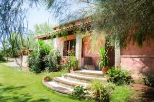 a house with stairs in front of a yard at Agriturismo Il Paradiso in Iglesias