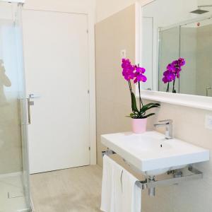 a bathroom with a sink and a vase with purple flowers at Flowers Sweet Rooms B&B in Vasto
