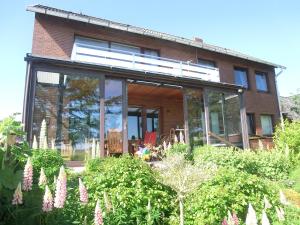 une maison avec des portes en verre et des fleurs devant elle dans l'établissement Haus Strandgut/2, à Duhnen