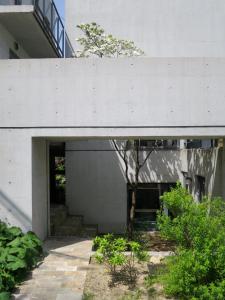 a white building with a tree in a courtyard at AH87 Osaka in Suita