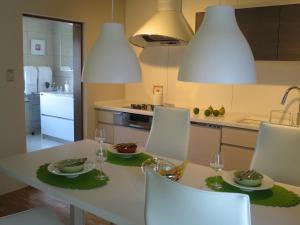 a kitchen with a white table with chairs and glasses at AH87 Osaka in Suita