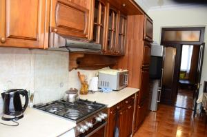 a kitchen with wooden cabinets and a stove top oven at Guest House Batumi Globus in Batumi