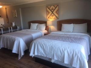 a hotel room with two beds with white sheets at The Waterfront Suites and Marina in Nanaimo