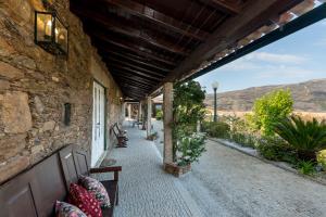 a stone building with a porch with benches on it at Casa da Encruzilhada in Ponte de Lima