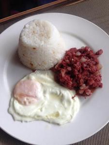 a plate of food with rice and an egg and meat at Lourdes Inn in Manila