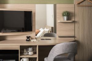 a room with a desk with two chairs and a television at Nest Hotel Hakata Station in Fukuoka