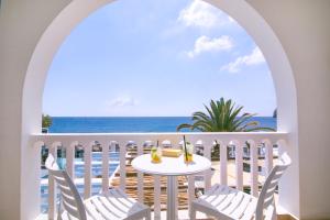 a table and chairs on a balcony with a view of the ocean at Hotel Sunshine in Kamari