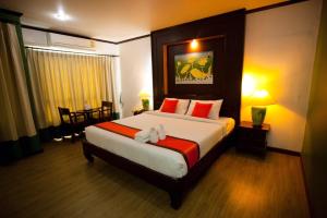 a bedroom with a large bed with red pillows at Chour Palace Hotel in Mae Sai