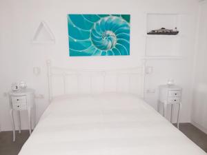 a white bedroom with a white bed and a painting on the wall at Elia Sea Home in Agios Romanos