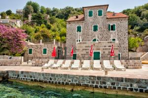 a group of chairs and umbrellas in front of a building at Apartments Barizon in Lustica