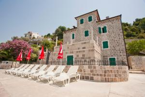 a row of chairs and red umbrellas in front of a building at Apartments Barizon in Lustica