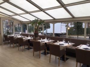 a dining room with tables and chairs and windows at Hotel Heritage in De Haan