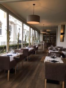 a dining room with tables and chairs and windows at Hotel Heritage in De Haan