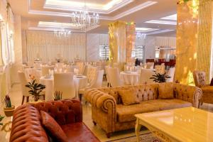 فندق عمار غراند في باكو: غرفة بها طاولات وأرائك وغرفة بها طاولات وكراسي