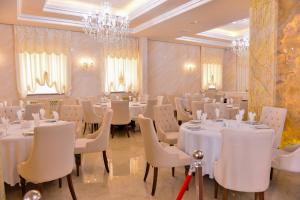 restauracja z białymi stołami i krzesłami oraz żyrandolem w obiekcie Ammar Grand Hotel w mieście Baku