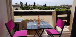 - une table avec 2 verres et une bouteille de vin sur le balcon dans l'établissement Studio Naturiste "LE CACTUS" Coursives Port Nature 614, au Cap d'Agde