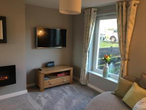 ein Wohnzimmer mit einem TV und einem Fenster in der Unterkunft 25 Windsor Crescent in Portree