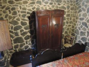 a wooden cabinet in a stone room with a bed at Rural House Etna in Castiglione di Sicilia