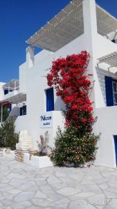 a white building with red flowers on the side of it at Nicos Studios & Apartments in Logaras