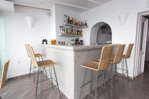 un bar con taburetes de ratán en una habitación en Sunset Hotel, en Firostefani