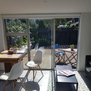 a room with chairs and a table and a sliding glass door at Near the shore in Waikanae