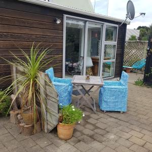 un patio con sillas, mesa y plantas en Near the shore, en Waikanae
