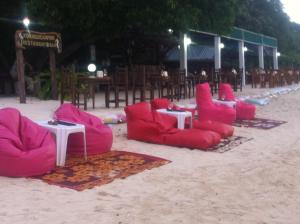 a group of red chairs and tables on the beach at Koh Ngai Camping Restaurant @ Bar in Ko Ngai