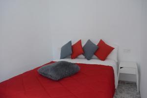 uma cama com um cobertor vermelho e almofadas em Cas Padrins em Can Picafort