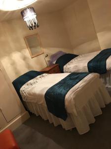 two twin beds in a room with a chandelier at Ingleton M'S Apartment in Ingleton