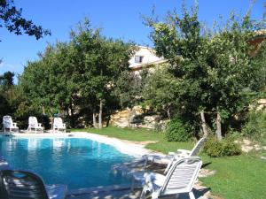 a swimming pool with lawn chairs and a house at Les Restanques in Goult