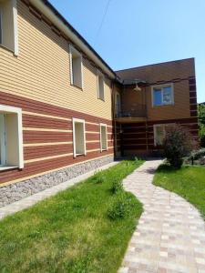 a house with a grass yard next to a building at Arcobaleno Home in Kyiv