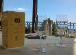 two wine glasses sitting on a table next to a box at Hotel Primavera Dell'Etna in Zafferana Etnea