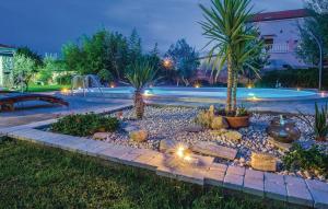 a garden with palm trees and a pool at night at Villa Surać in Murvica