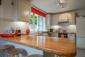 a kitchen with white cabinets and a wooden counter top at La Maison Muguet in Civray