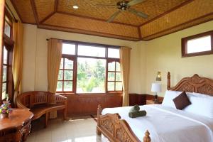 a bedroom with a large bed and a large window at Ganesha Ubud Inn in Ubud