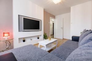 a living room with a couch and a tv on a wall at Apartment Matea in Split