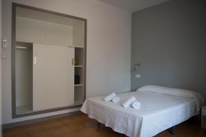 a white bed sitting in a bedroom next to a white wall at Hostal Ripoll Ibiza in Ibiza Town