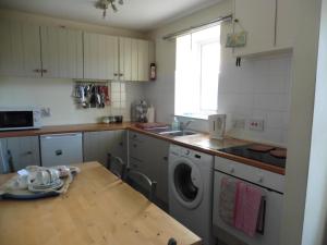 a kitchen with a sink and a washing machine at Mews Cottage in Middleton in Teesdale