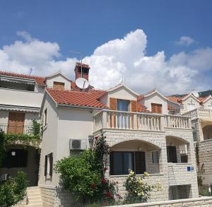 a white house with a balcony on top of it at Apartments Benika in Bol
