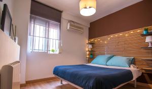 a bedroom with a blue bed and a window at Utopia Home Alameda in Seville