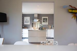 a kitchen with white cabinets and a large mirror at La Colline des Renards Chambres in Locmaria-Berrien