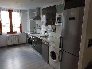 a kitchen with a stainless steel refrigerator and a washer and dryer at Casa Ponet in Valencia de Aneu