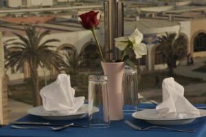 a blue table with plates and a vase with a rose at Hotel Riad Ben Atar in Essaouira