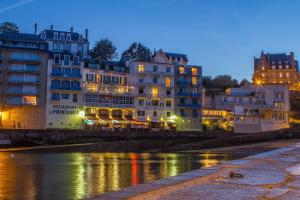 un groupe de bâtiments à côté d'une rivière la nuit dans l'établissement Hôtel-Restaurant Printania, à Dinard