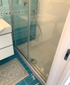 um chuveiro com uma porta de vidro na casa de banho em delizioso appartamento con terrazzetta em Porto Ercole